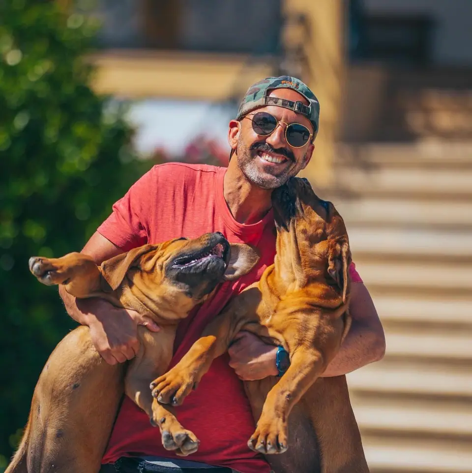 Rui Navarro segurando dois Boerboels jovens ao ar livre